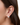 Close-up of an ear wearing a silver ball earring with a blurred background