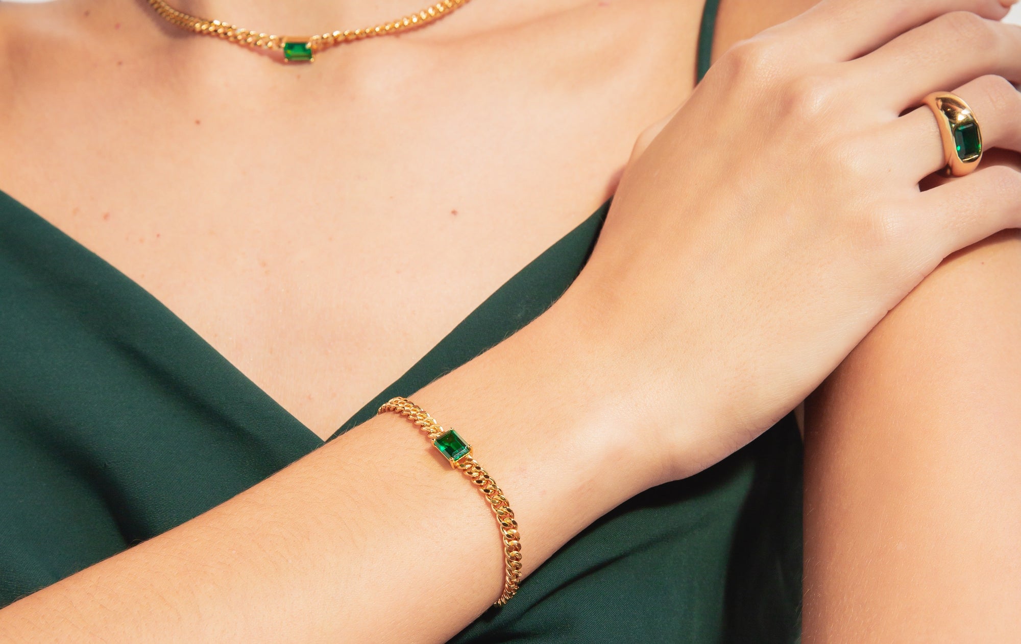 woman wearing a green dress and gold emerald jewelry