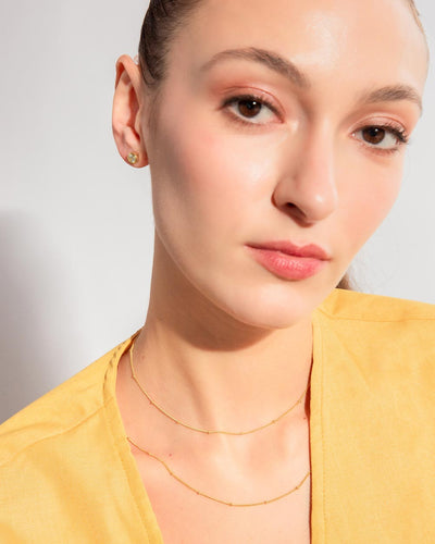 A woman wearing the Lia Studs, Louisa Choker, and Louisa Necklace layered together
