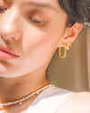 A woman wearing an oval-shaped gold hoop earring