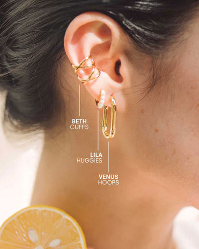 A pair of gold ear cuffs, an opal huggie, and an oval-shaped gold hoop earring