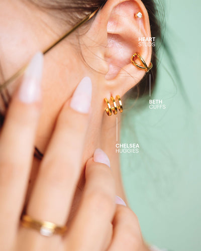 A labeled shot of the Chelsea Huggies, Beth Cuffs, and Heart Studs worn on a woman's ear