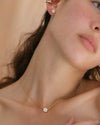 A woman wearing the Flora Necklace and Flora Studs