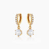 The Julia Huggies, gold drop earrings featuring a shining crystal suspended from dainty pavé-set huggies