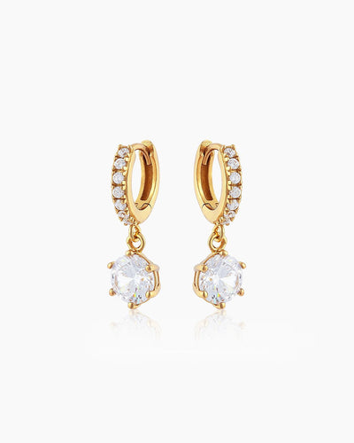 The Julia Huggies, gold drop earrings featuring a shining crystal suspended from dainty pavé-set huggies