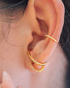 A gold illusion earring that looks like two earrings and a gold ear cuff