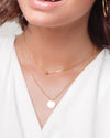 A close up shot of a woman wearing the Sofia Necklace and gold hoops