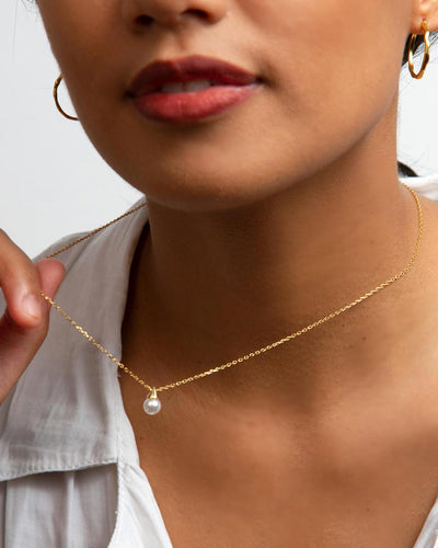 A woman wearing the Alicia Necklace and gold hoops